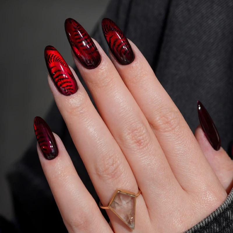 Ongles rouges et noirs cat eye avec motif fougère