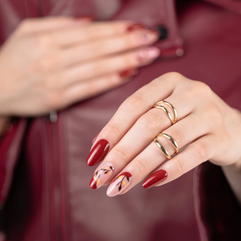 Ongles rouges avec motif végétal sur base laiteuse