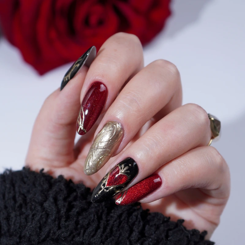 Red and black nails with metallic gold details in a Vamp Romantic style
