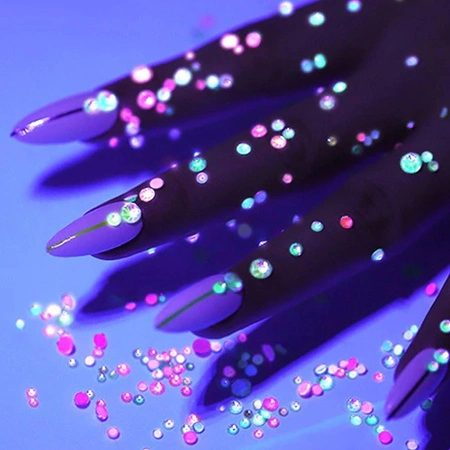 wykonane w ciemności zdjęcie eksponujące manicure ze świecącymi w ciemności cyrkoniami