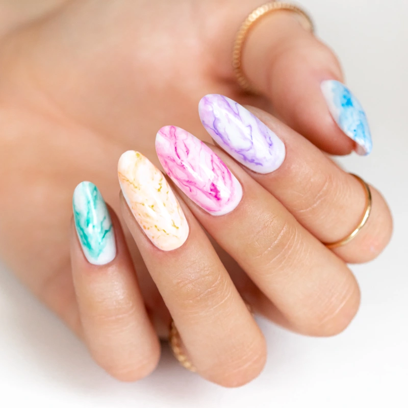 Pastelowy marmurkowy manicure na migdałowych paznokciach w odcieniach turkusu, żółci, różu, fioletu i błękitu