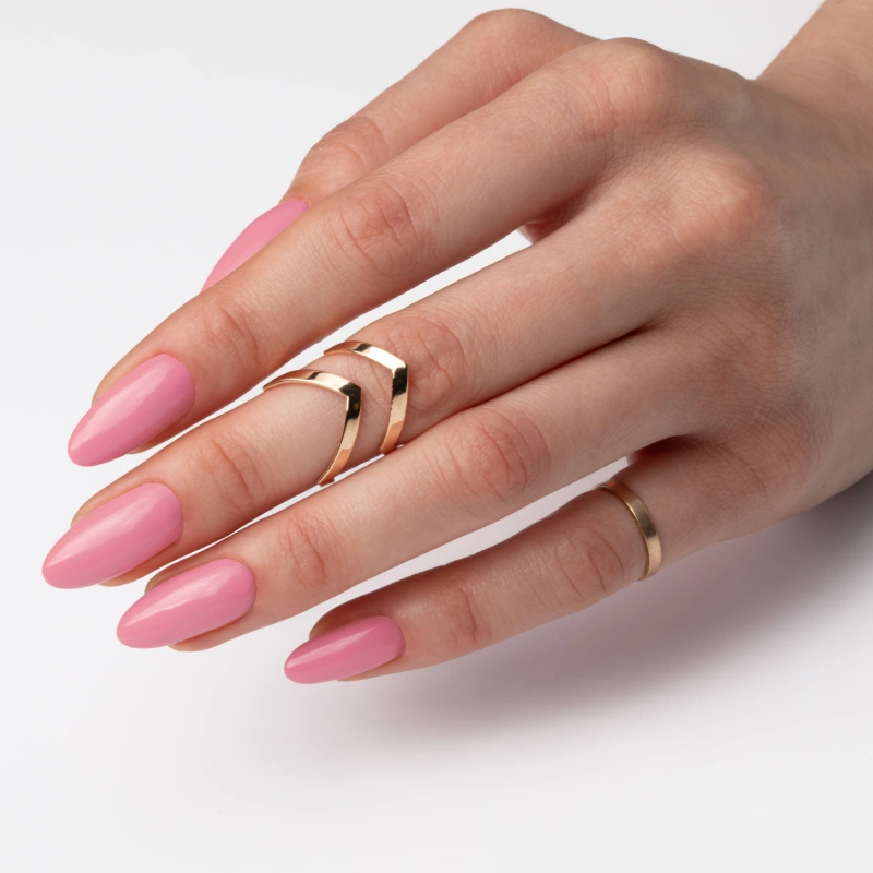 Pastelowy różowy manicure na długich migdałkach ze złotymi pierścionkami