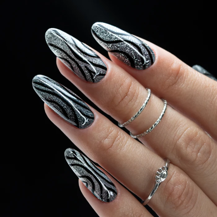 Silver Swirl Nails na długich migdałkach z czarnymi liniami i brokatowym wykończeniem