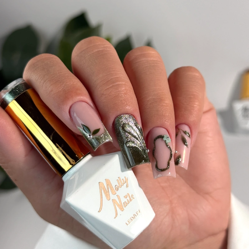 Zielone paznokcie z liśćmi, metalicznym zdobieniem 3D i butelką lakieru Molly Nails.